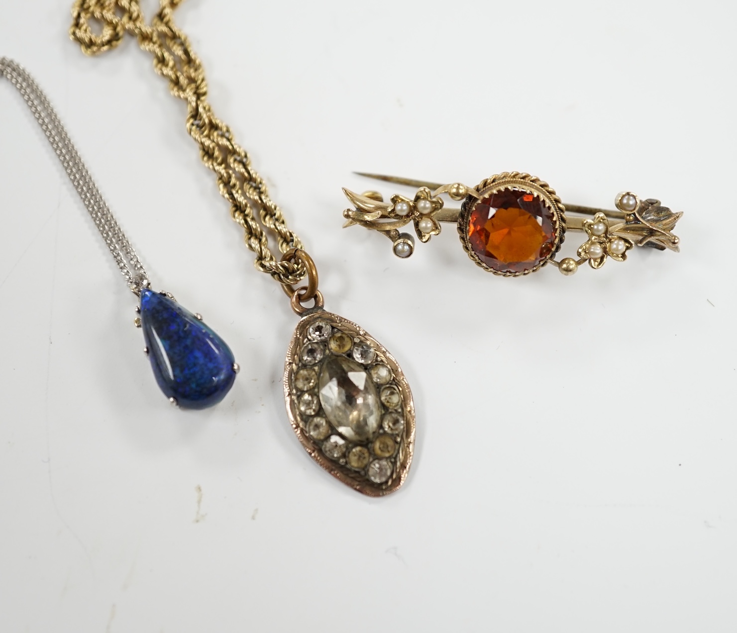 A 15ct and citrine set brooch, paste set pendant on a 9ct gold rope twist chain and a modern white metal and simulated opal set pendant, on a 9ct white gold chain.